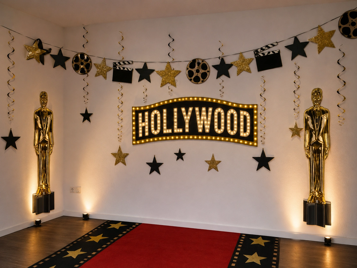 Elegante Hollywood-Wanddekoration mit beleuchtetem Hollywood-Schriftzug, goldenen Oscar-Statuen, Filmrollen und Sternengirlanden – ein stilvoller Blickfang, der den Partyraum in die Atmosphäre einer glamourösen Filmpremiere verwandelt.